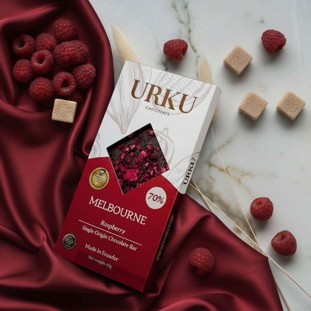 URKU Melbourne Raspberry chocolate bar packaging on a marble surface with raspberries and chocolate pieces. Lifestyle rasbpberry experience.
